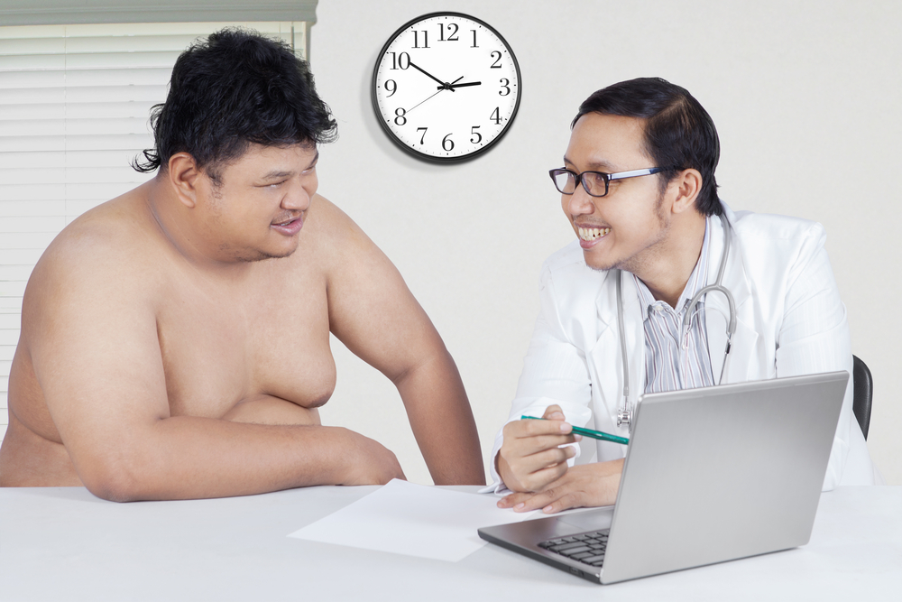 رجل من أصحاب الوزن الزائد يتحدثان مع طبيب في عيادة

