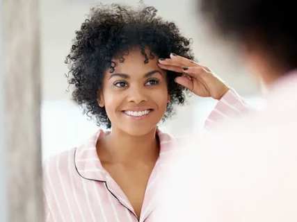 صورة لامرأة تنظر في المرآة وتبتسم بعد ظهور ملامح أكثر شبابًا.